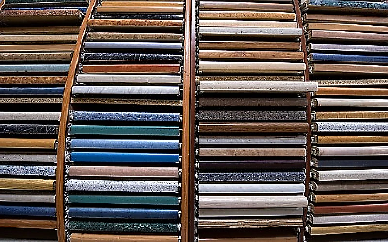 Ausstellung mit zahlreichen Fliesenmustern in verschiedenen Farben und Oberflächen, übersichtlich in gebogenen Regalen angeordnet.